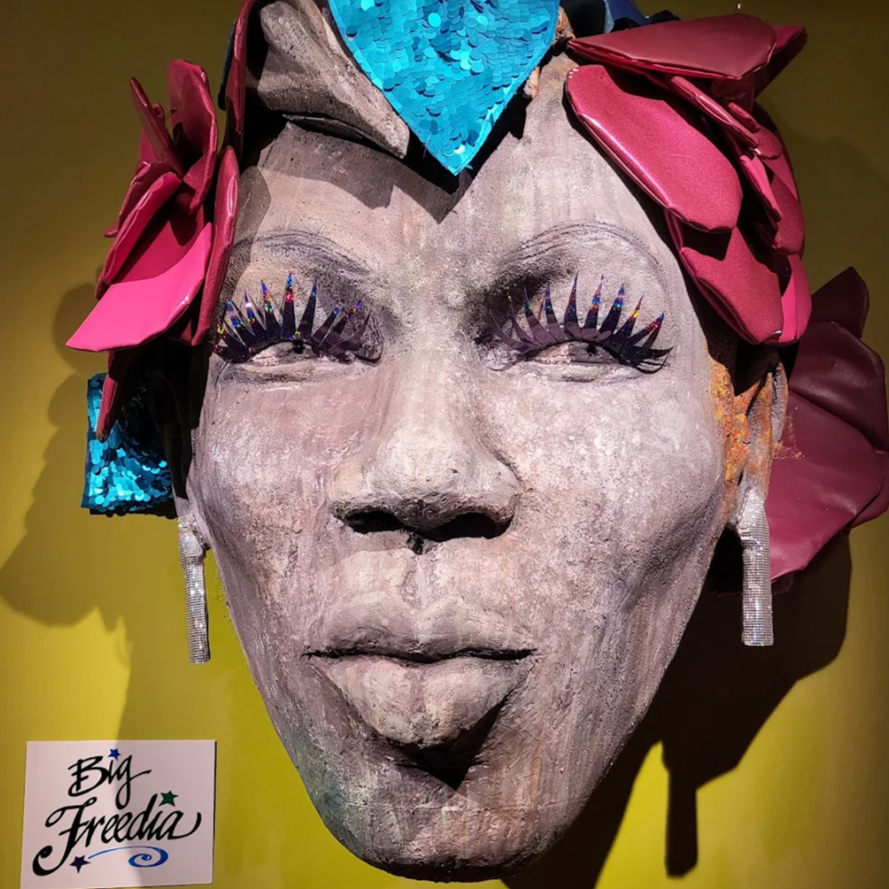 Decorative Big Freedia-themed exhibit bust with a floral headband at JAMNOLA
